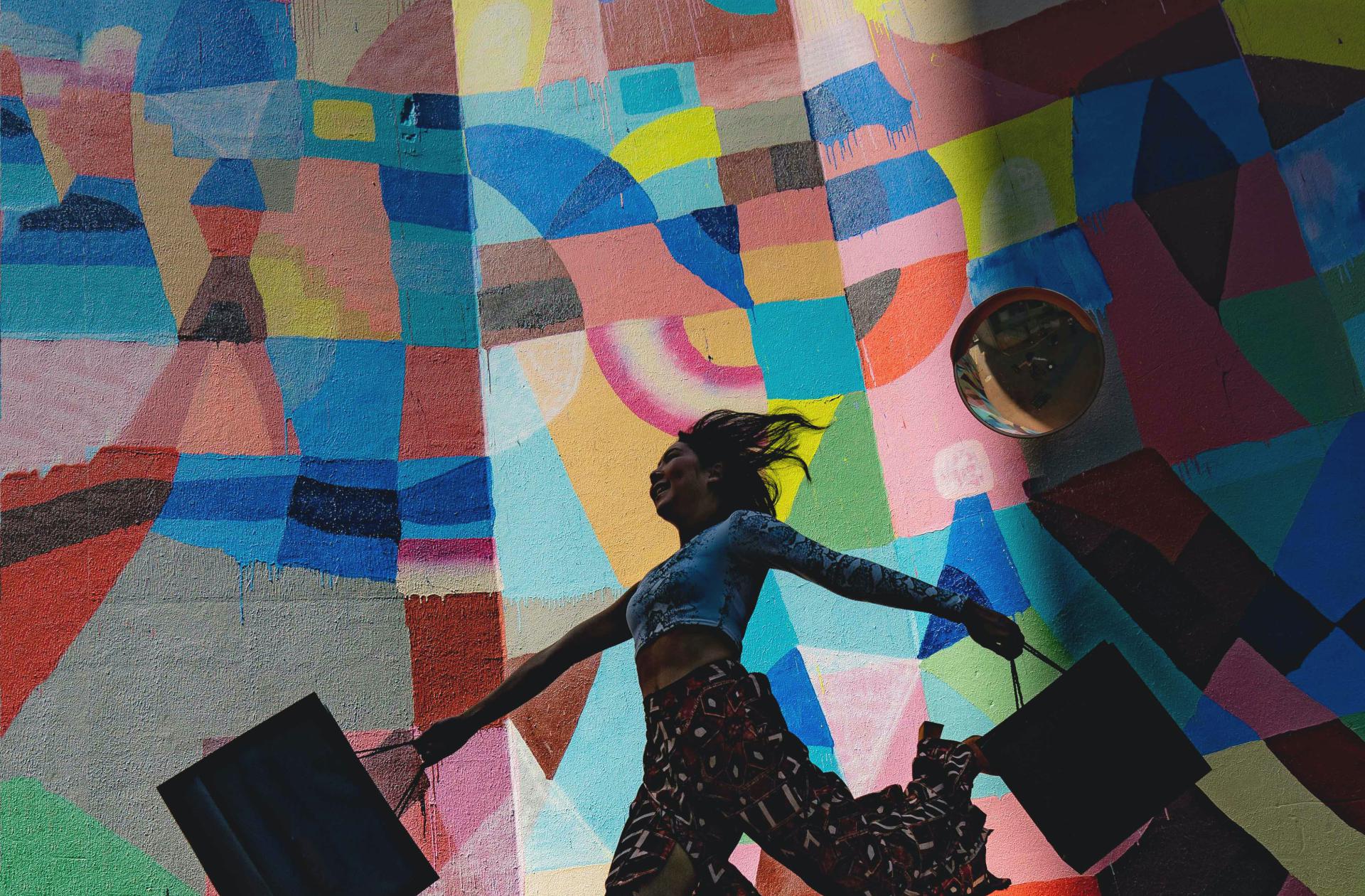 Beeld dame met winkeltassen kleurrijke mural